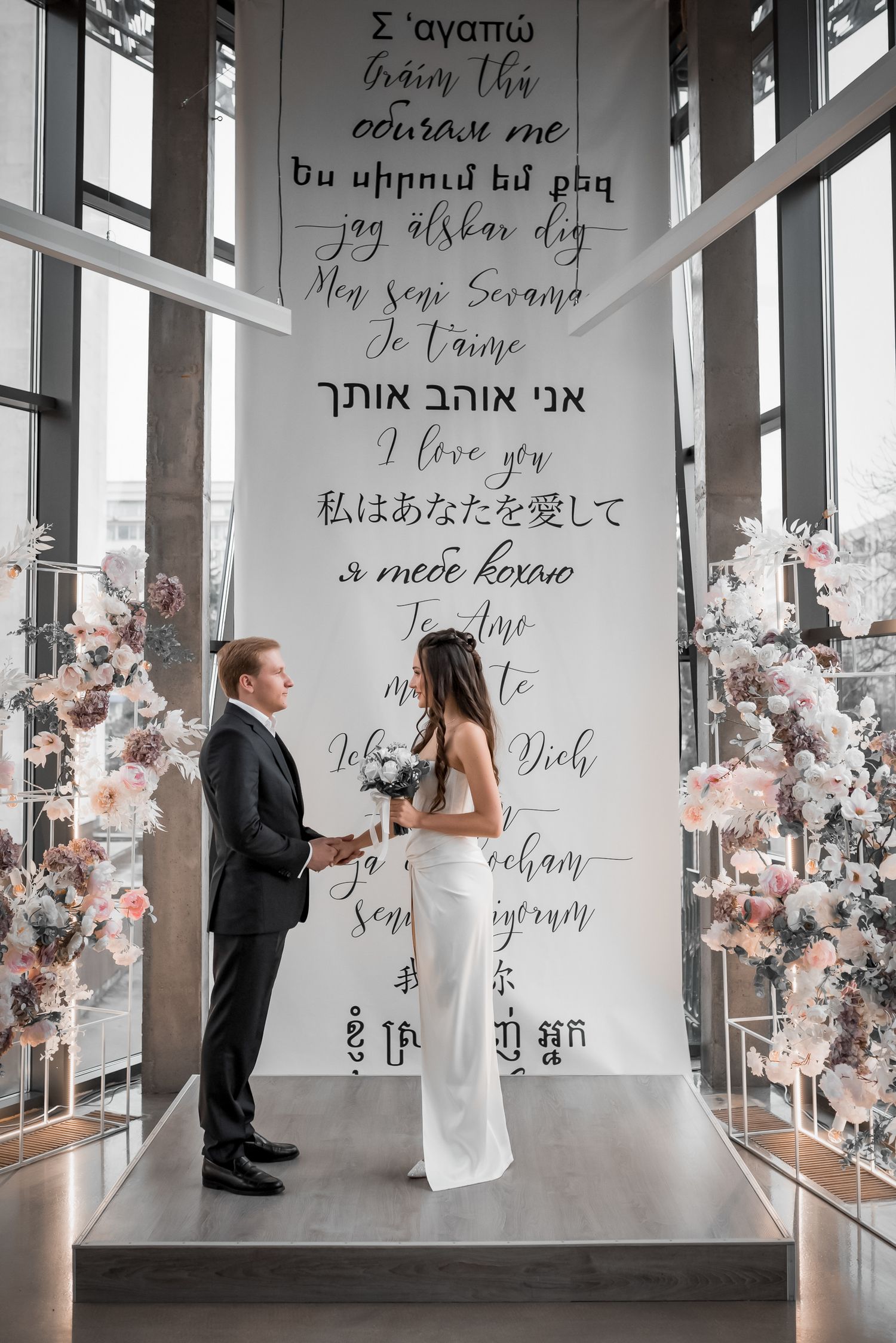 Modern wedding ceremony setup with wall art featuring 'I love you' in multiple languages.