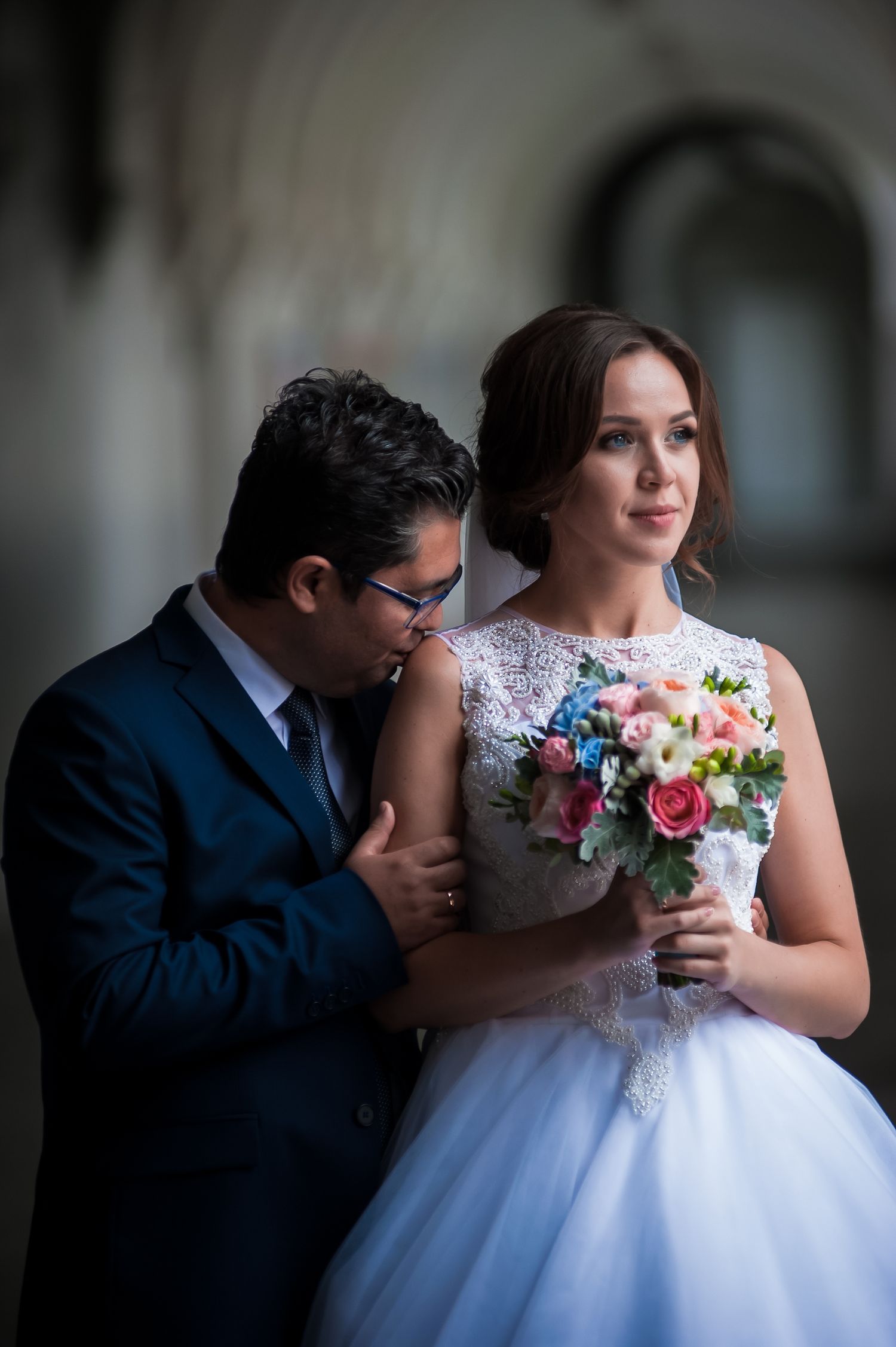 Intimate wedding portraits featuring a beautiful bouquet of colorful flowers against soft indoor lighting.