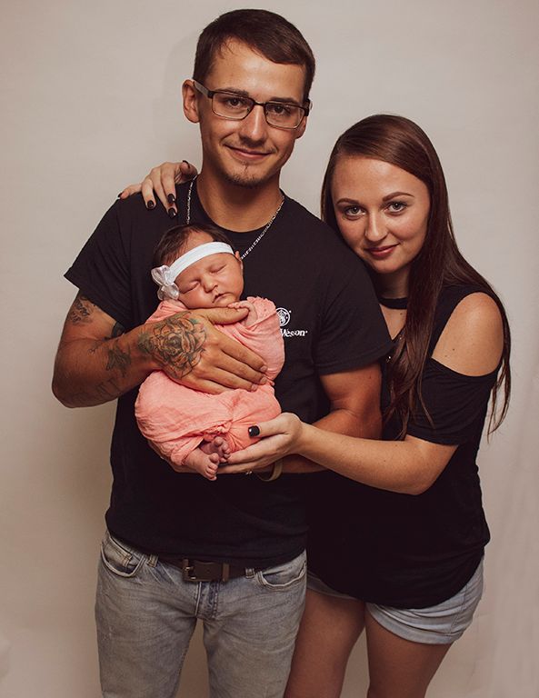 Family of three holding their newborn