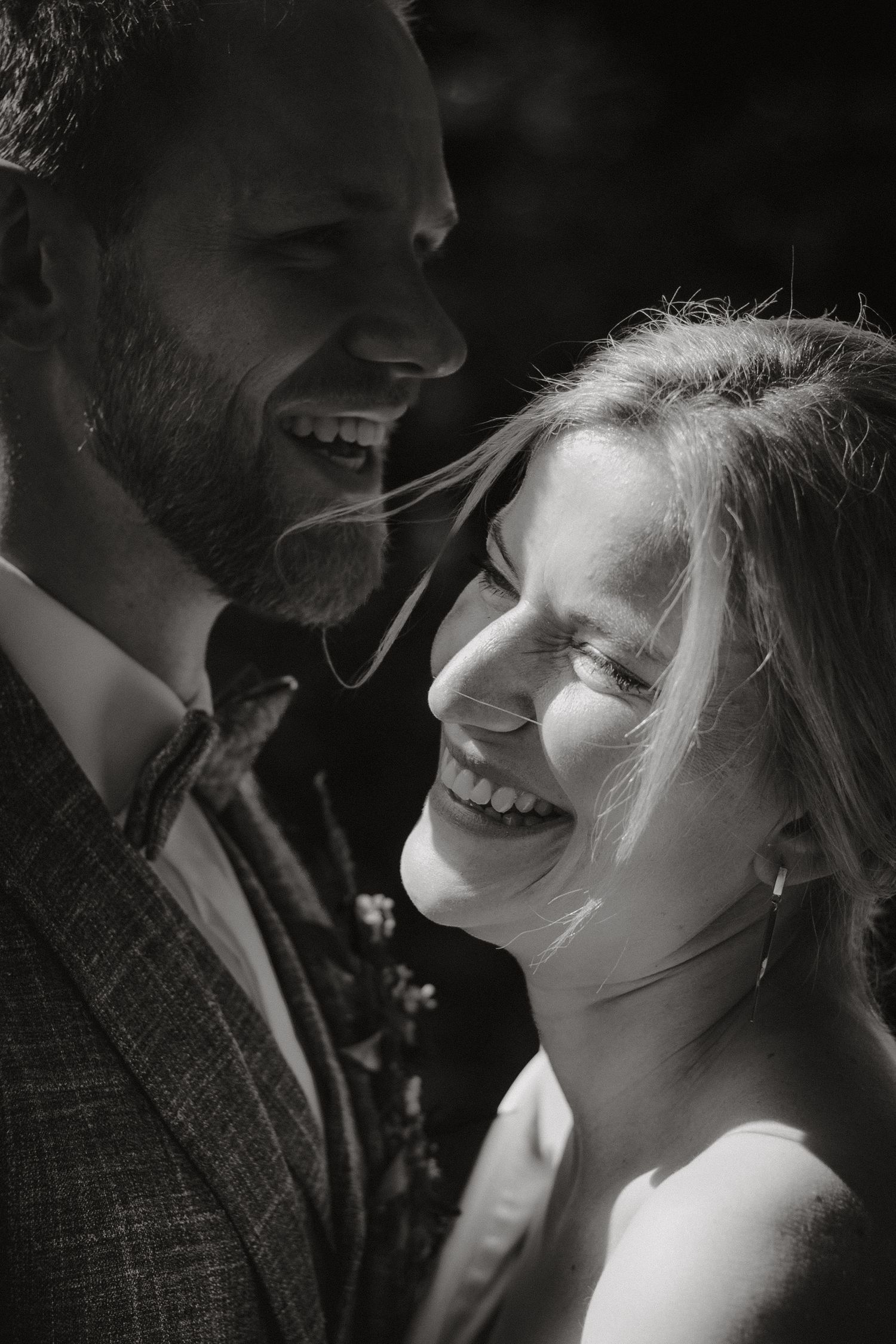 Intimate black and white portrait of newlyweds sharing joyful laughter.