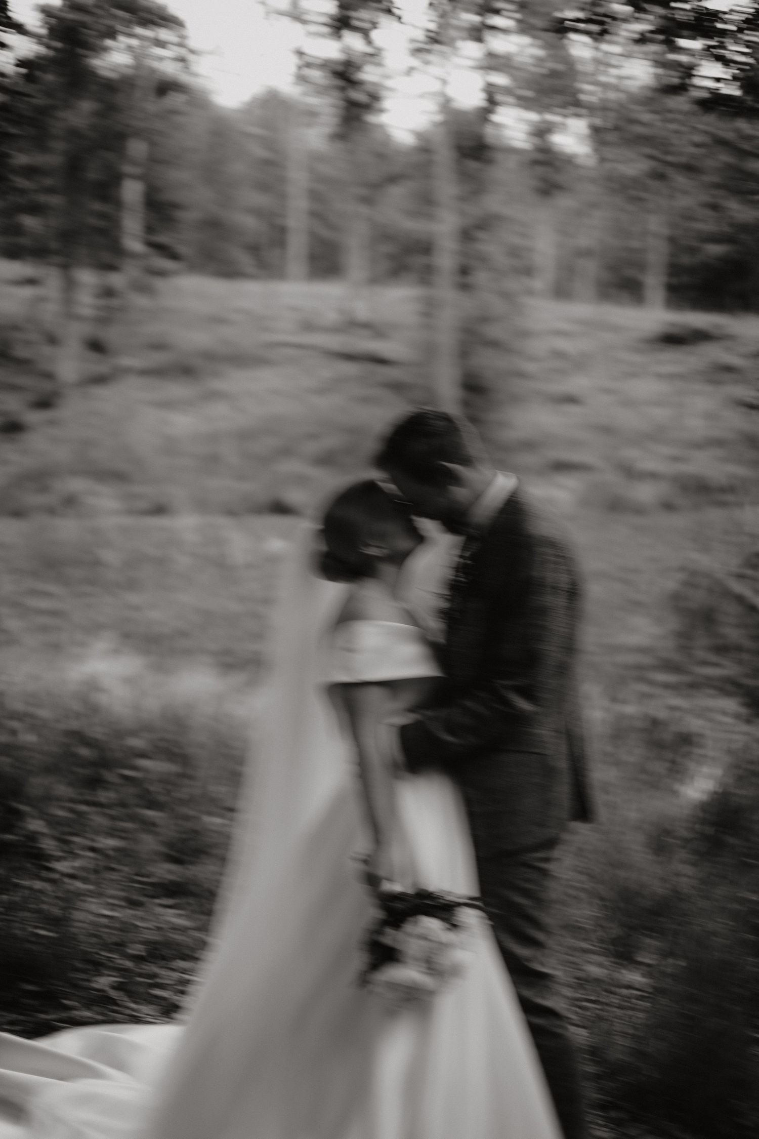 Motion-blurred artistic wedding photo capturing movement in a wooded setting.