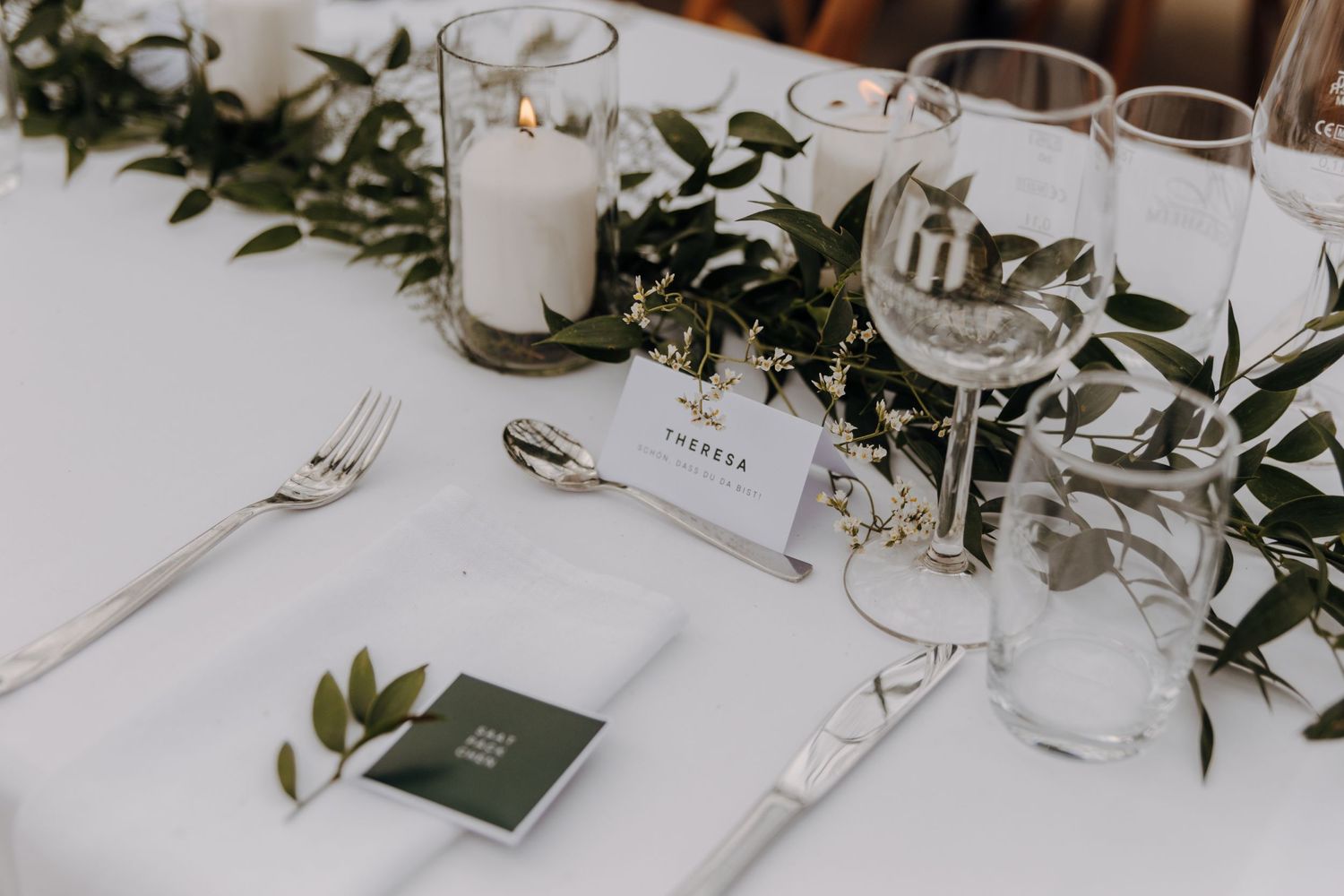Elegant table setting with greenery and place settings for wedding reception.