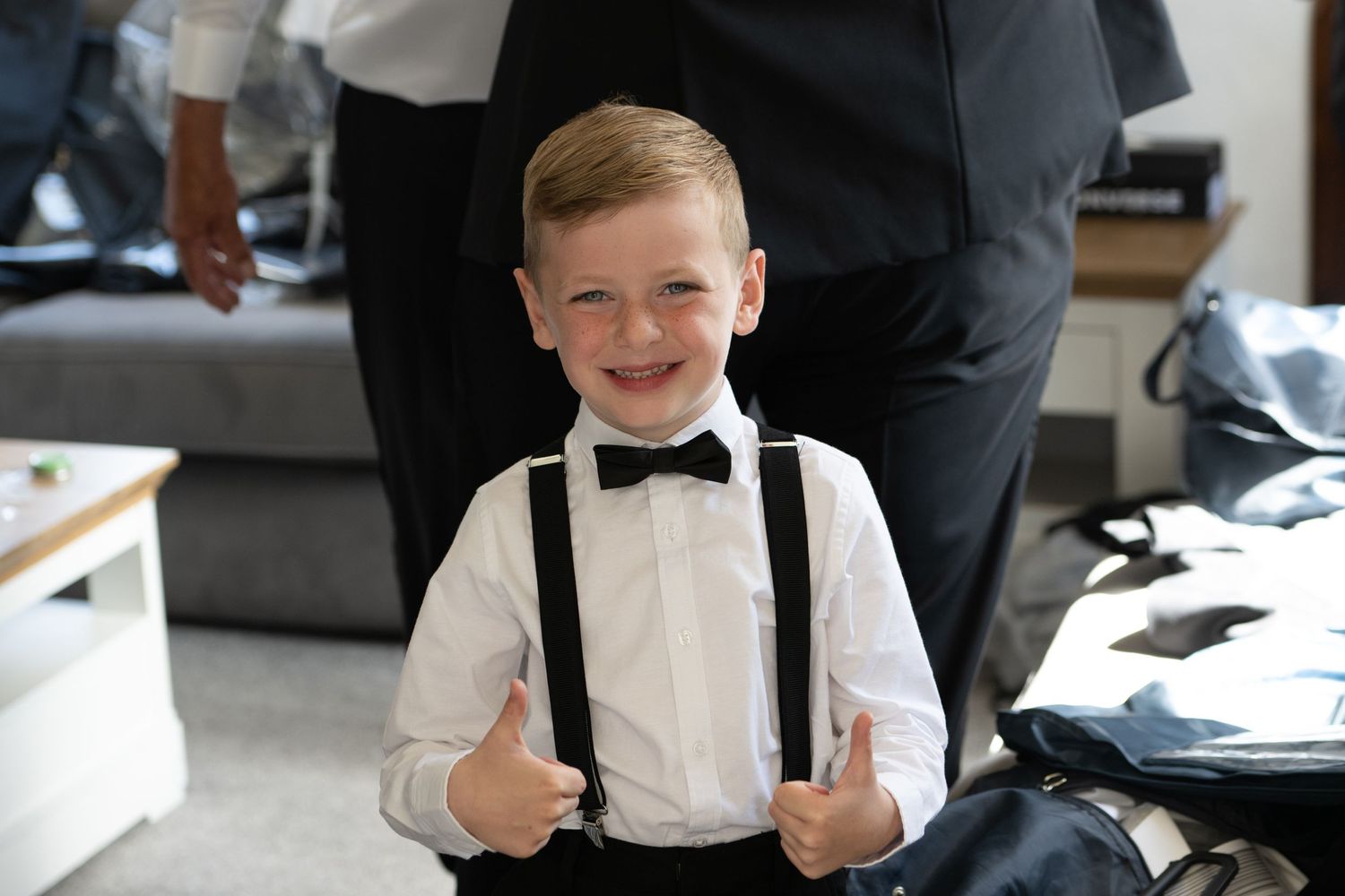 Young attendant in white shirt and suspenders giving thumbs up with a cheerful expression.
