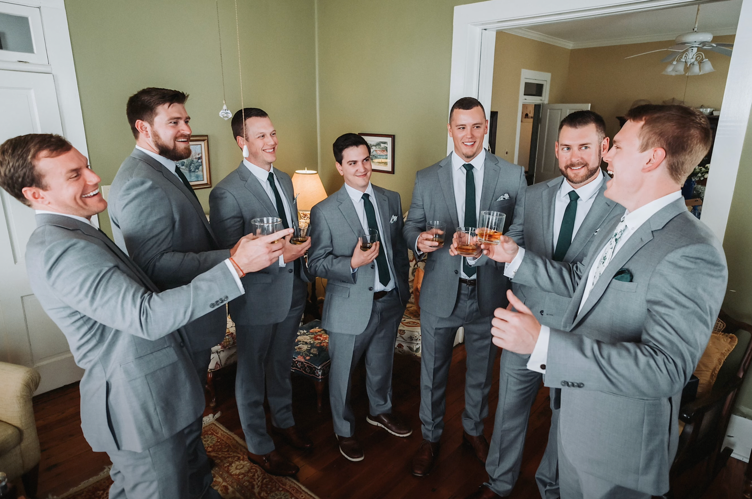 Groomsmen in gray suits gathering for drinks and conversation.