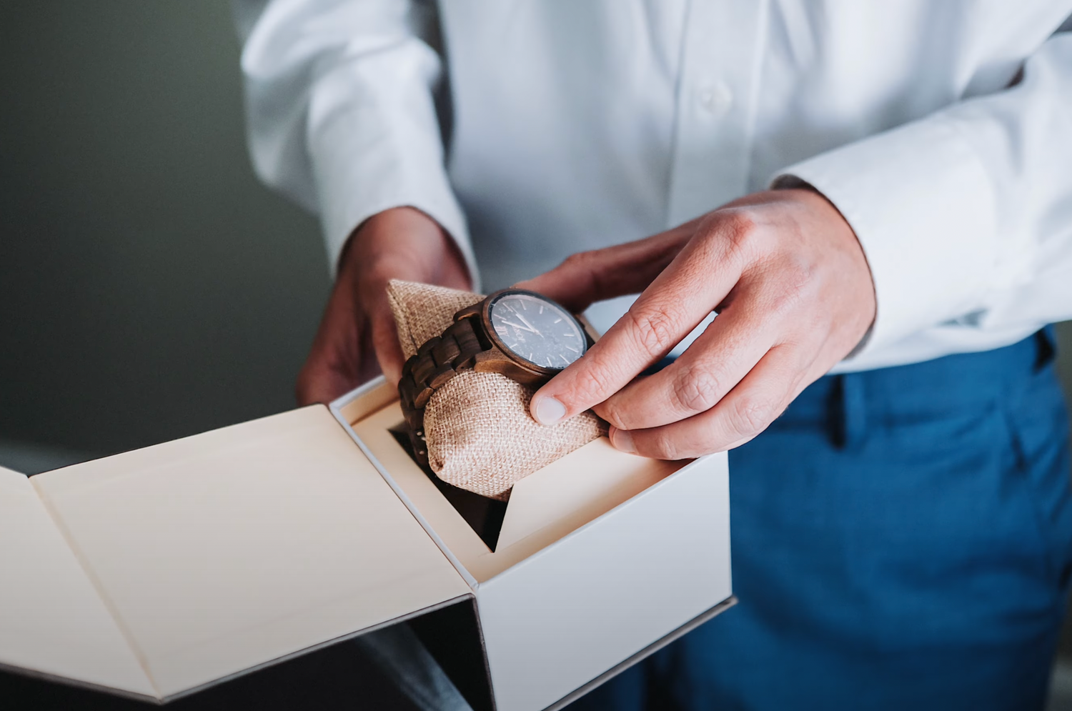 Hands carefully opening a decorative watch box with delicate detail.