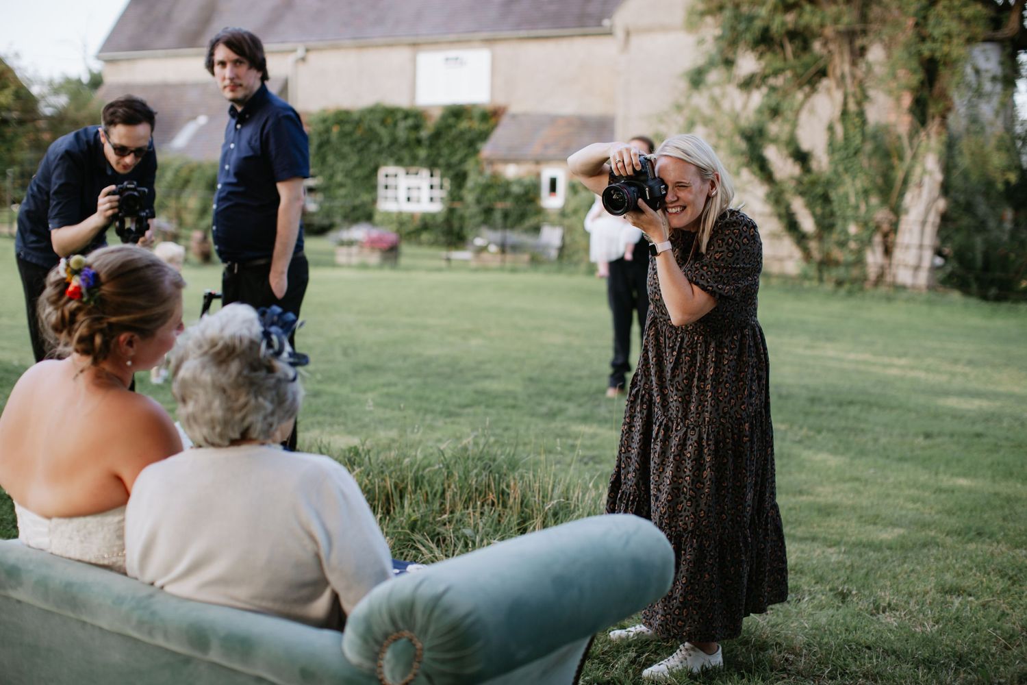 A wedding photographer captures photos of guests during an outdoor celebration.