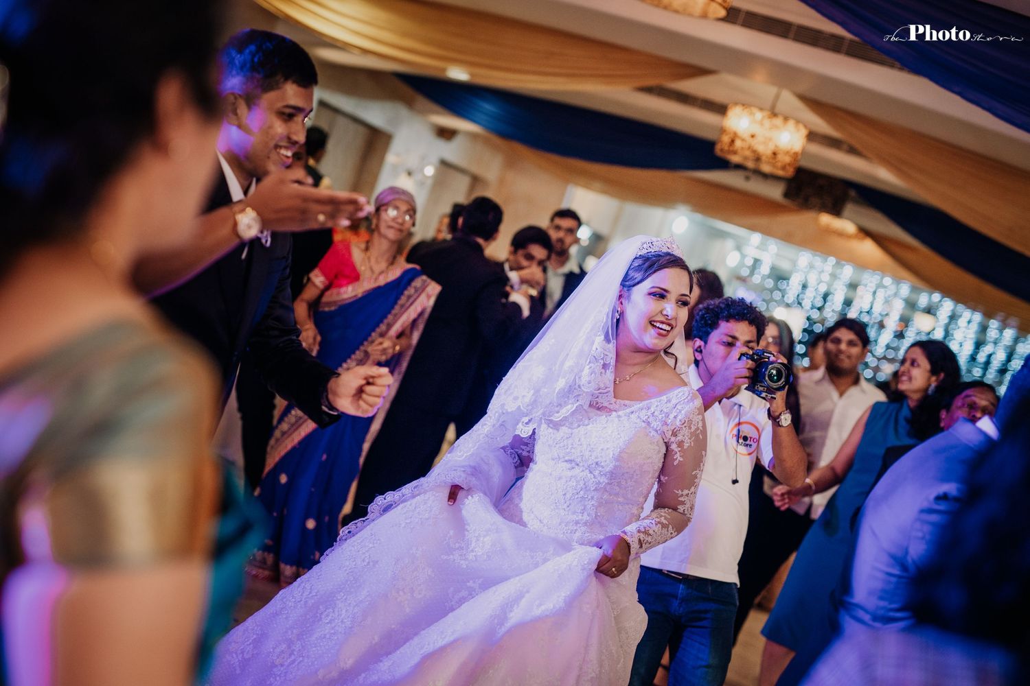 Wedding reception dance floor filled with guests under dramatic lighting and decor.