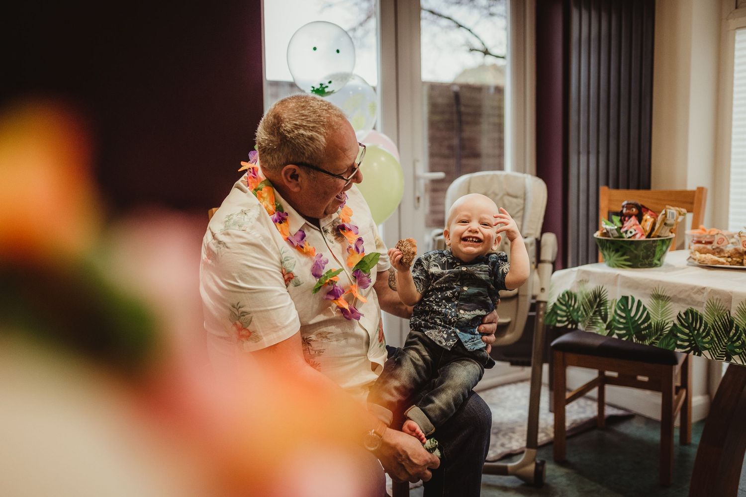 birthday boy sitting on his grandad's lap laughing