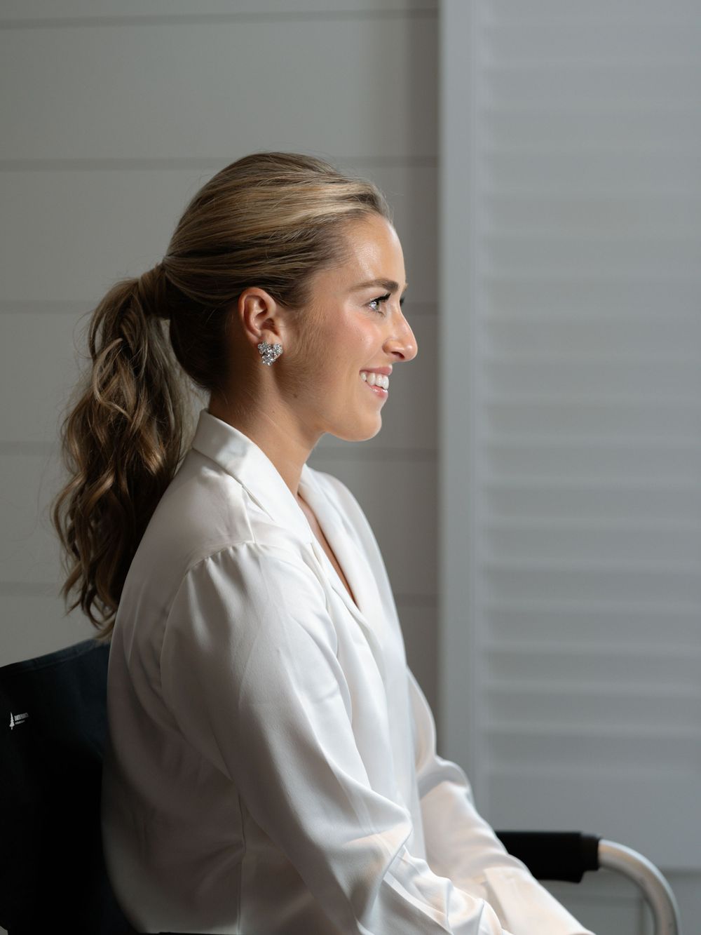 Profile view of person in white robe sitting by window.