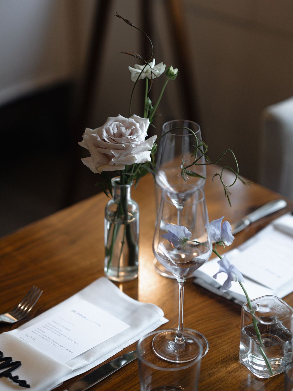 Intimate table setting with wine glasses, menus and floral arrangements.