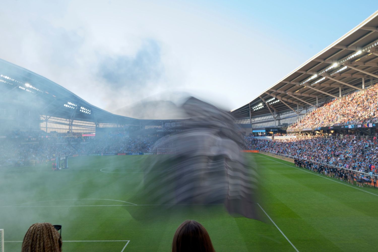 Soccer stadium filled with fans as dramatic smoke tifo display unfolds on the field.