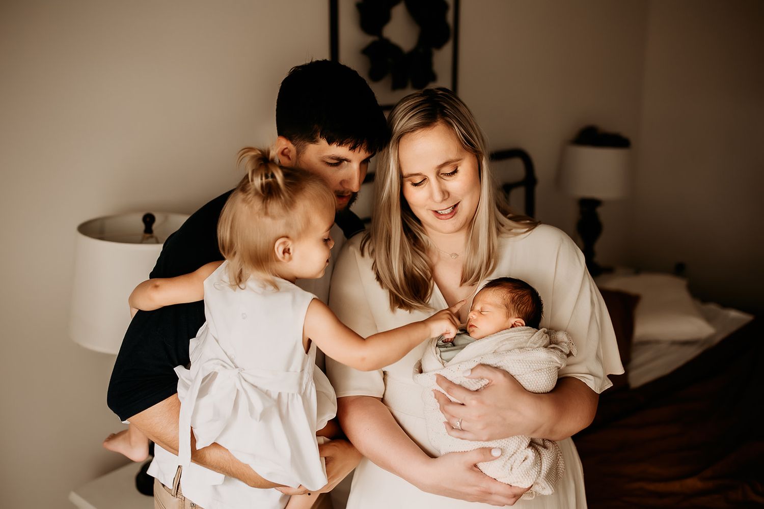 A family of four standing in the nursery looking at their new baby boy.