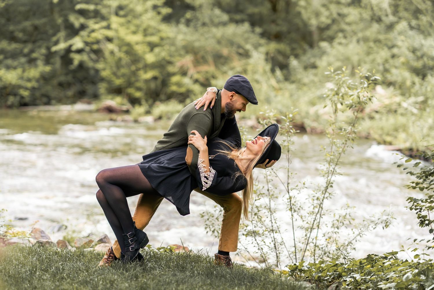 Playful outdoor engagement session by a stream with natural poses and candid moments.