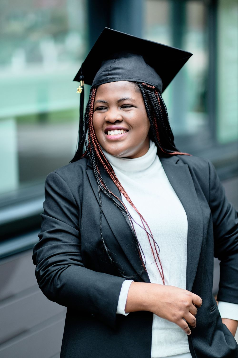 Graduate in black blazer and graduation cap shows joyful expression during celebration.