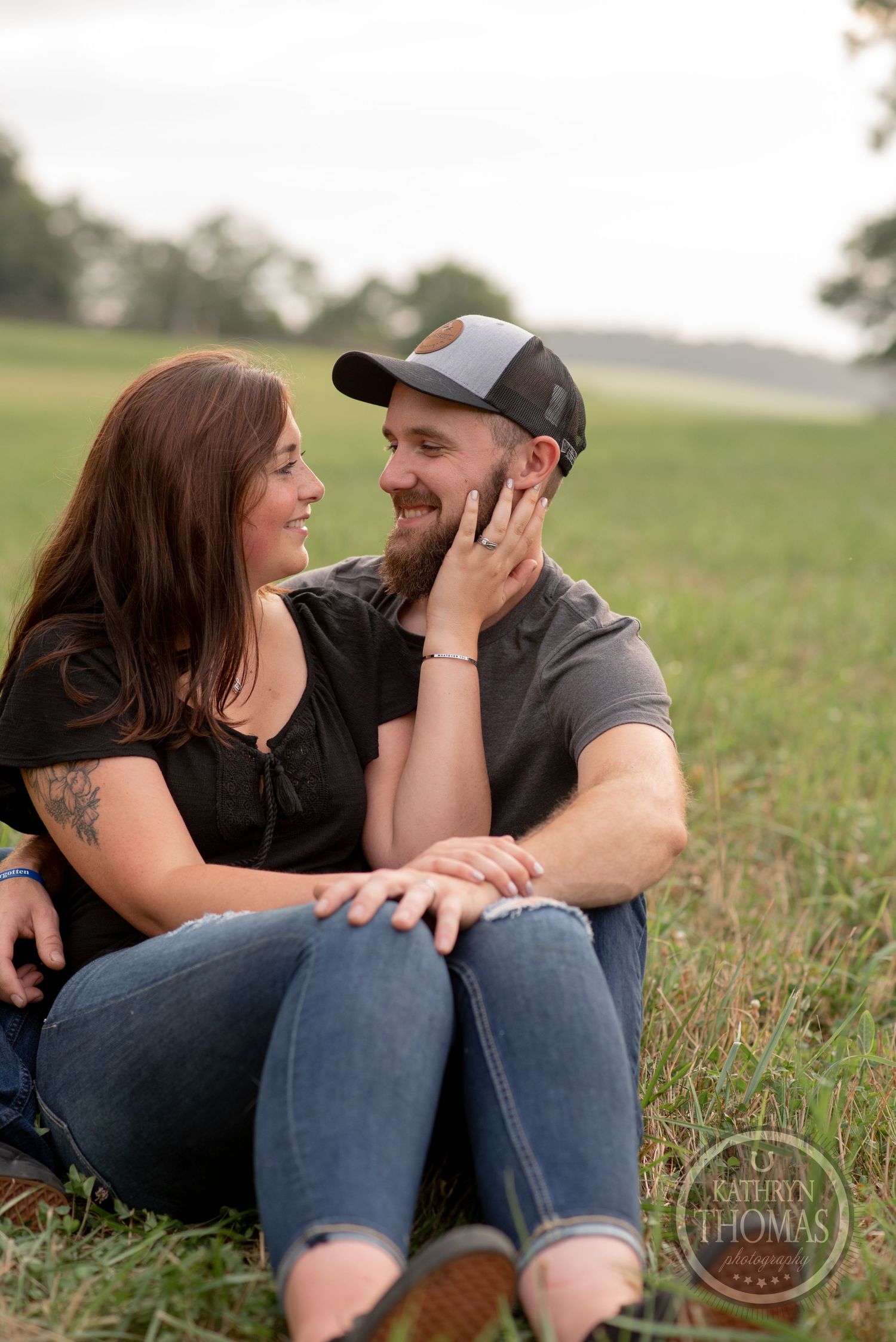 Couple shares affectionate moment while sitting in grassy field.