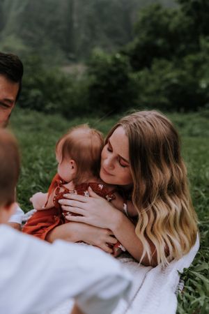 Intimate family moment captured against lush green mountain backdrop.