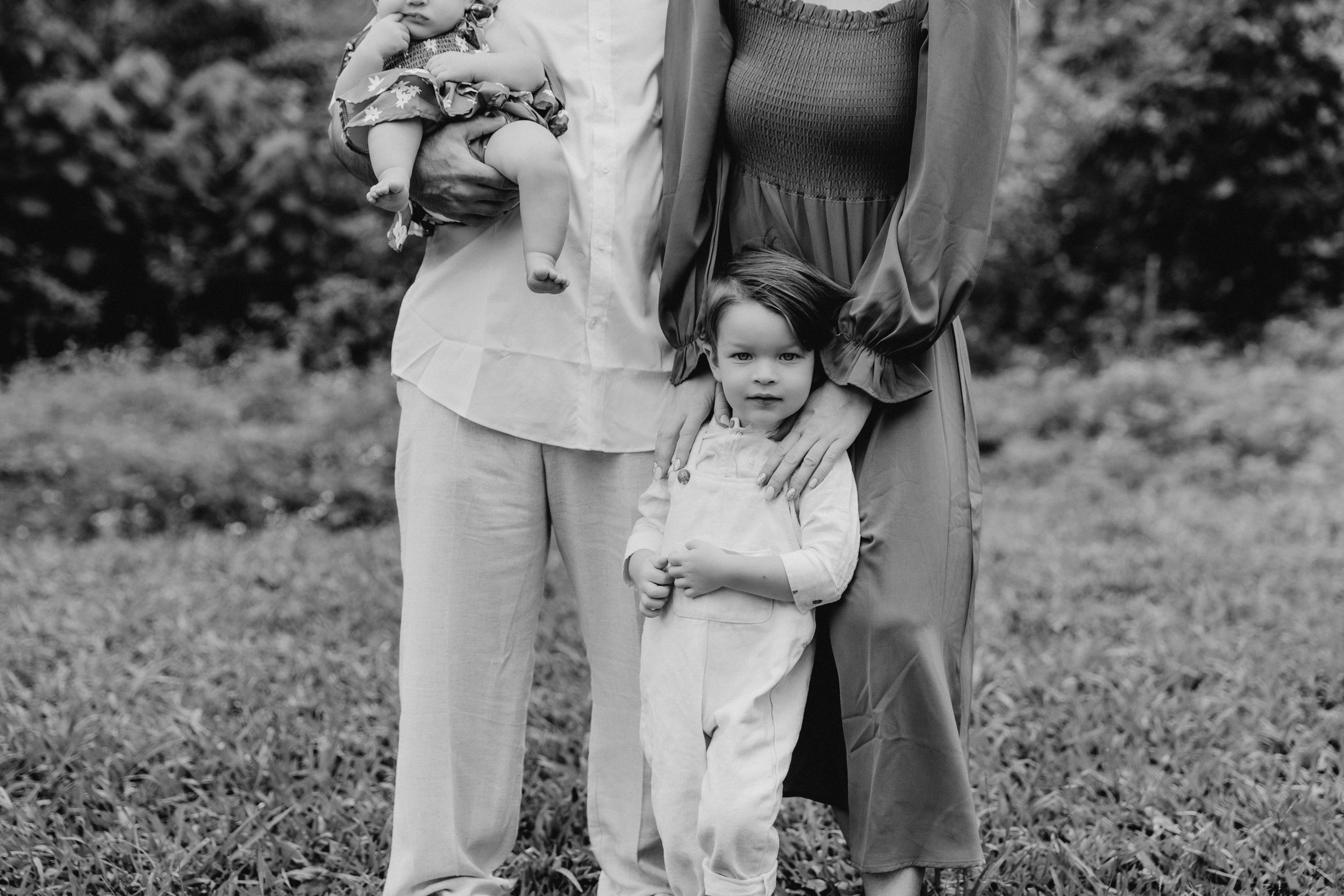 Black and white family photo with mountains and greenery in background.