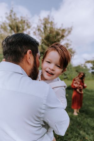 A heartwarming outdoor family moment with laughter and embraces against a natural backdrop.