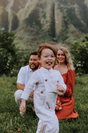 A joyful outdoor family portrait with mountains and greenery in the background.