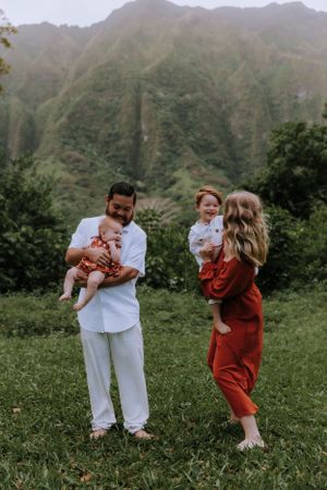 Playful family photo session showing parents and children laughing together in mountain setting.