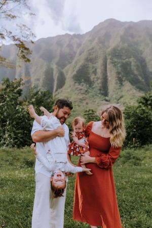 A playful family moment with energetic poses against a dramatic mountain landscape.