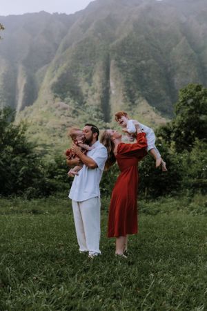 Family playfully posing together in a mountain meadow wearing coordinated outfits.