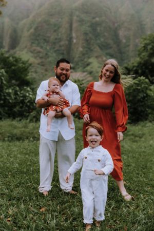 Candid family moment captured in green field with majestic mountain backdrop.