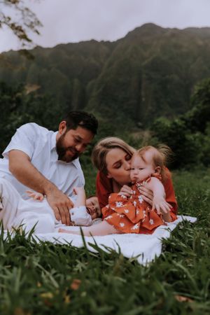 Family having a picnic on a blanket with dramatic mountain landscape in the background.