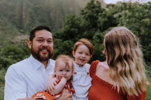 Family portrait session in a lush mountain setting with coordinated rust and white outfits.