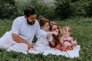 Family enjoying quality time together on white picnic blanket in grassy field.