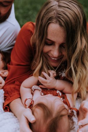Candid moment of joyful family bonding while lying on white blanket outdoors.