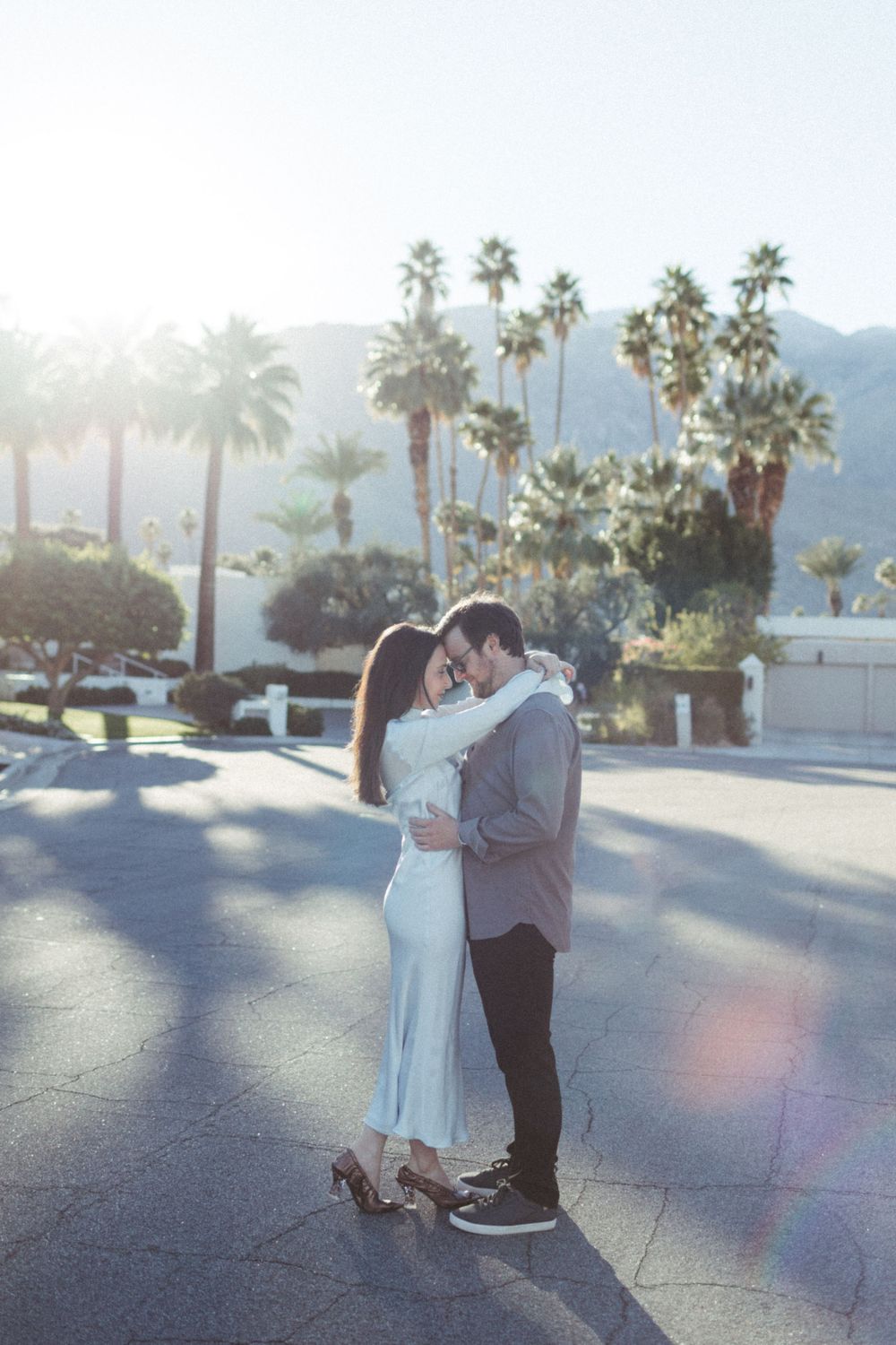 couple embraces each other on palm springs street for golden hour sunset photos