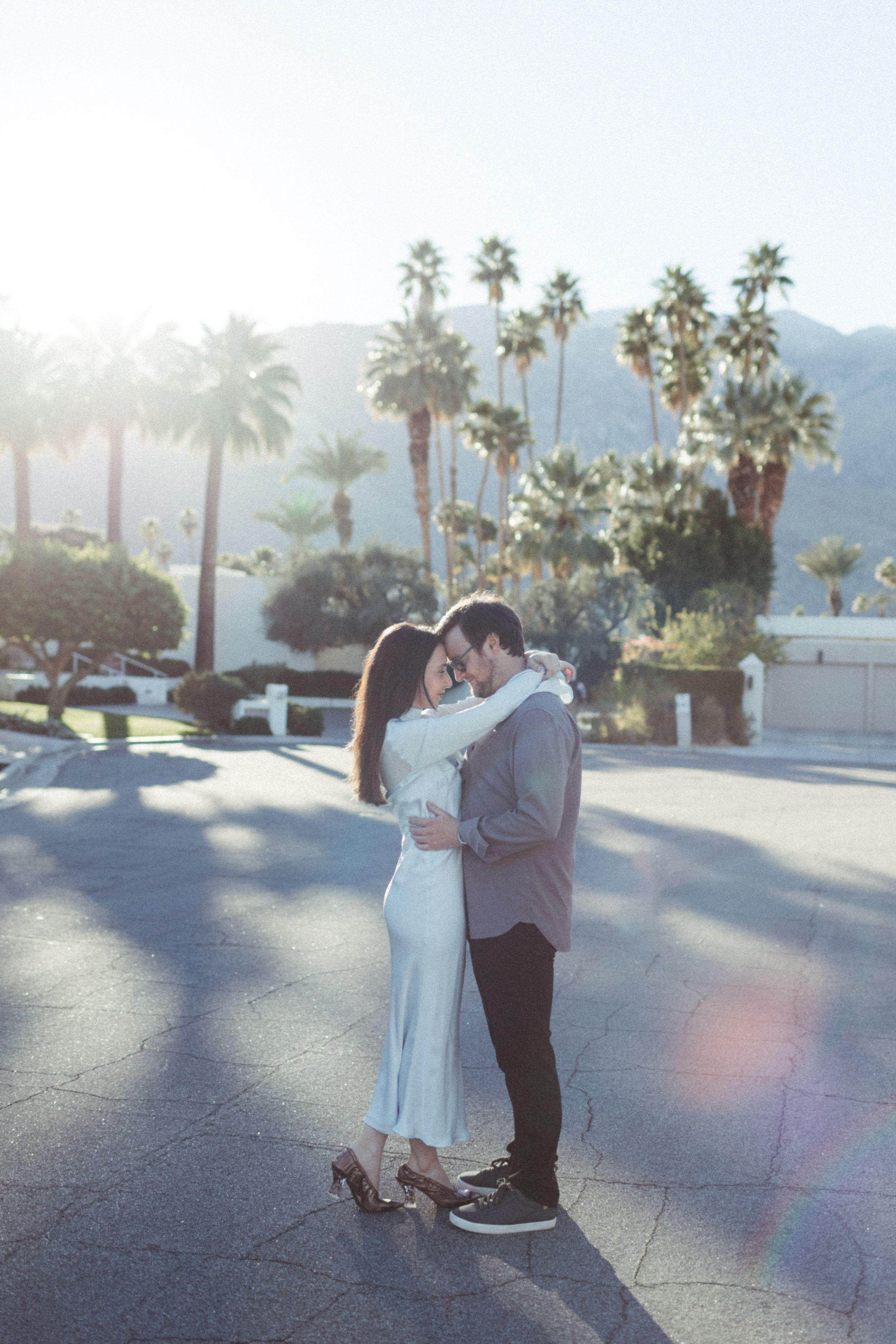 couple embraces each other on palm springs street for golden hour sunset photos