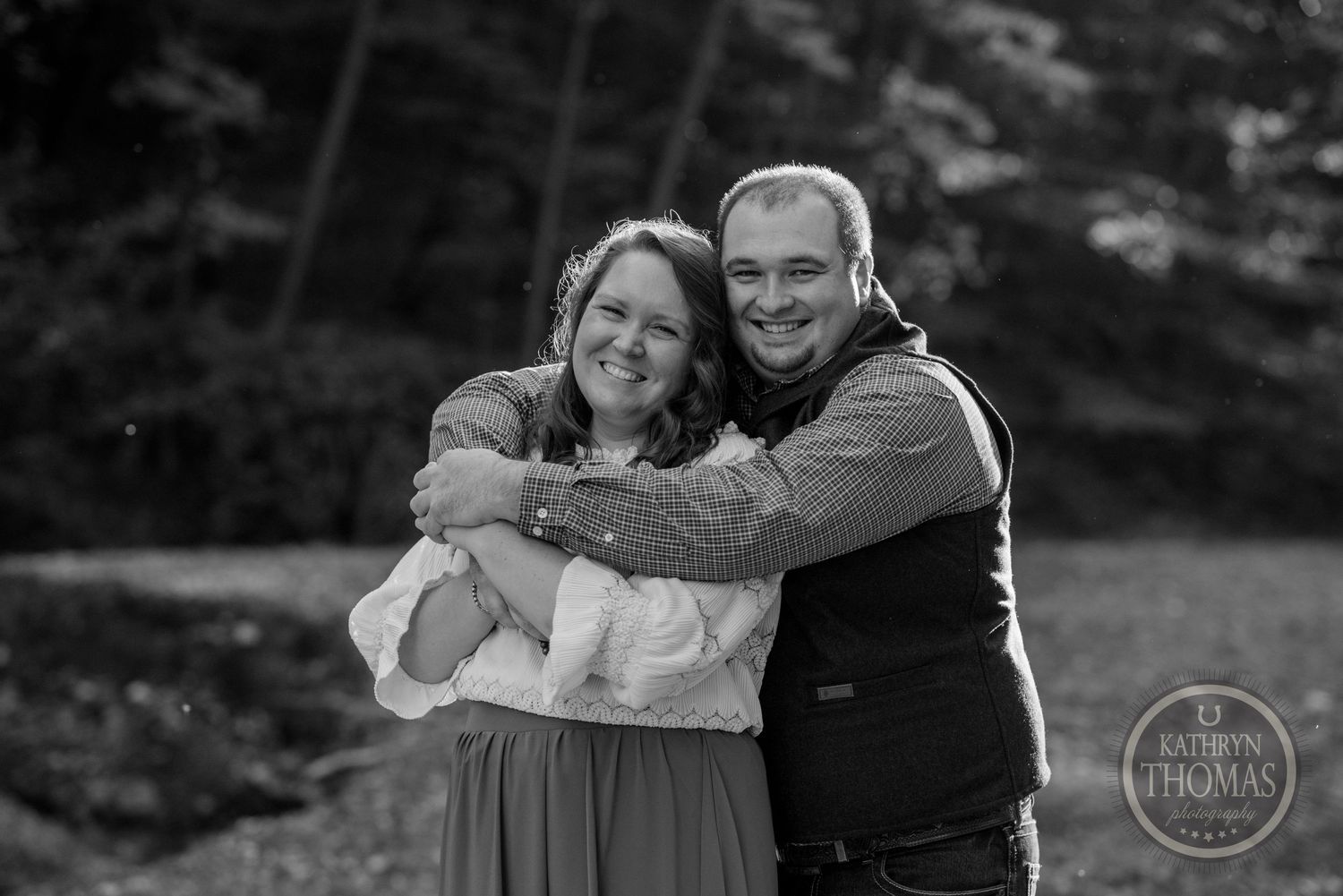 A black and white portrait of a joyful couple sharing a warm embrace outdoors.