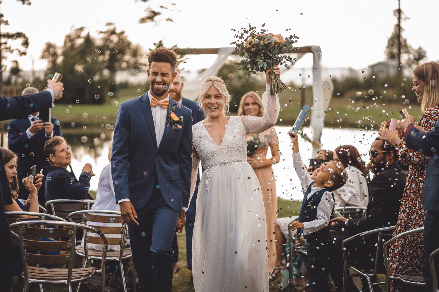 Brudpar går ut från ceremonin till musik glitter och konfetti och blir firade av släkt och vänner
