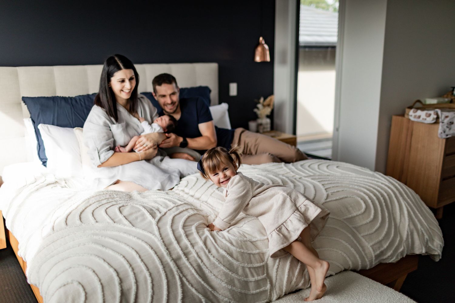 Family spending quality time together on a large bed with white bedding.