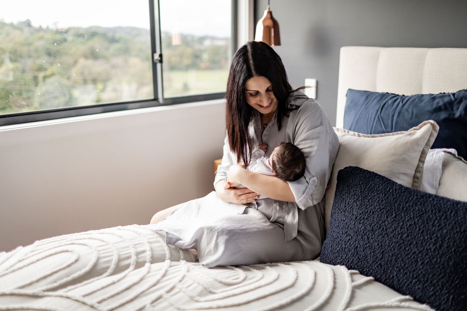A quiet moment with a newborn baby in a bright bedroom with modern decor.