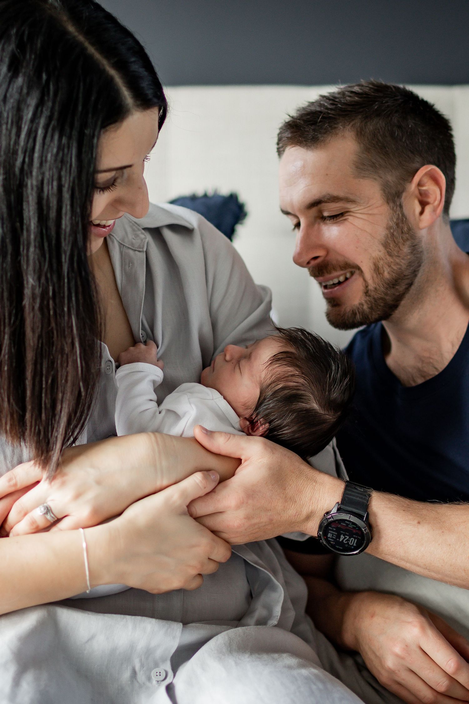 An intimate moment with parents and their newborn baby on a bed.