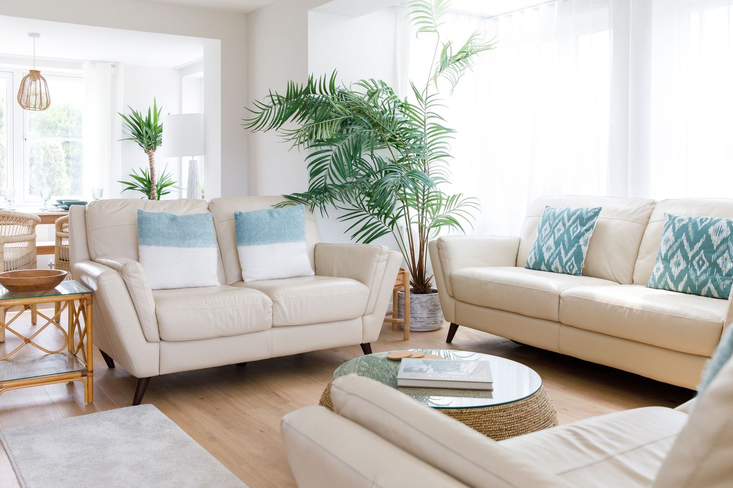 Bright modern living room with cream sofas, tropical plants, and coastal decor elements.