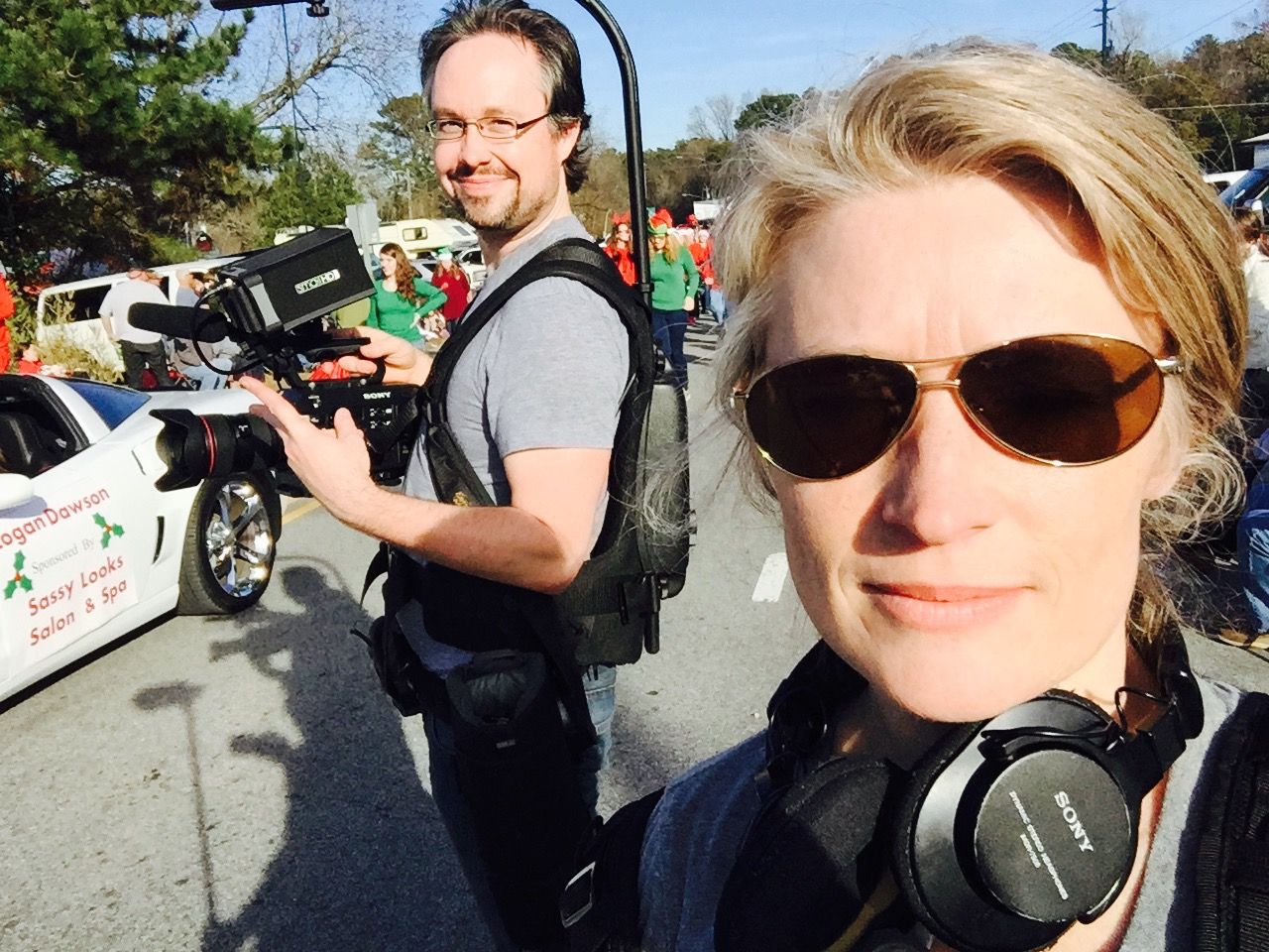 Two videographers with professional camera equipment working together outdoors on a sunny day.