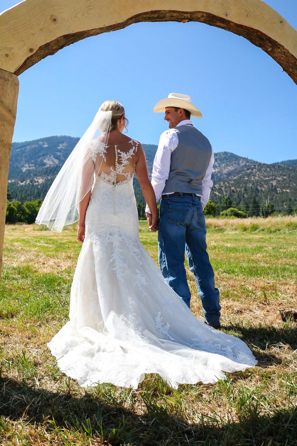 newlyweds holding hands under arch