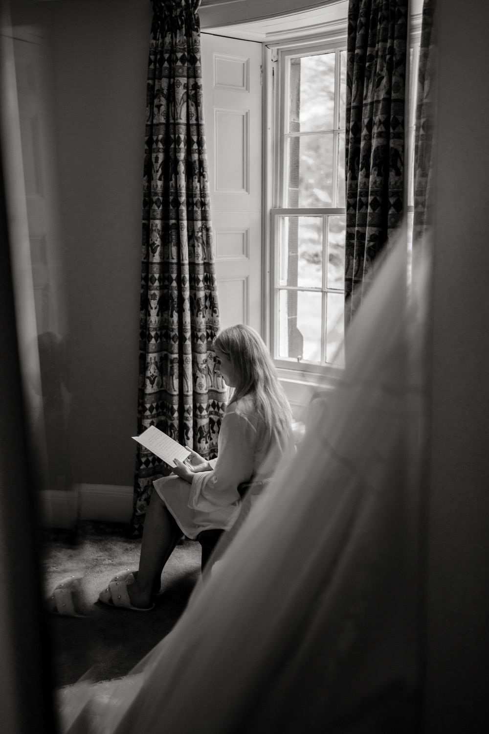 A quiet moment by the window with natural light streaming in showing wedding preparations.