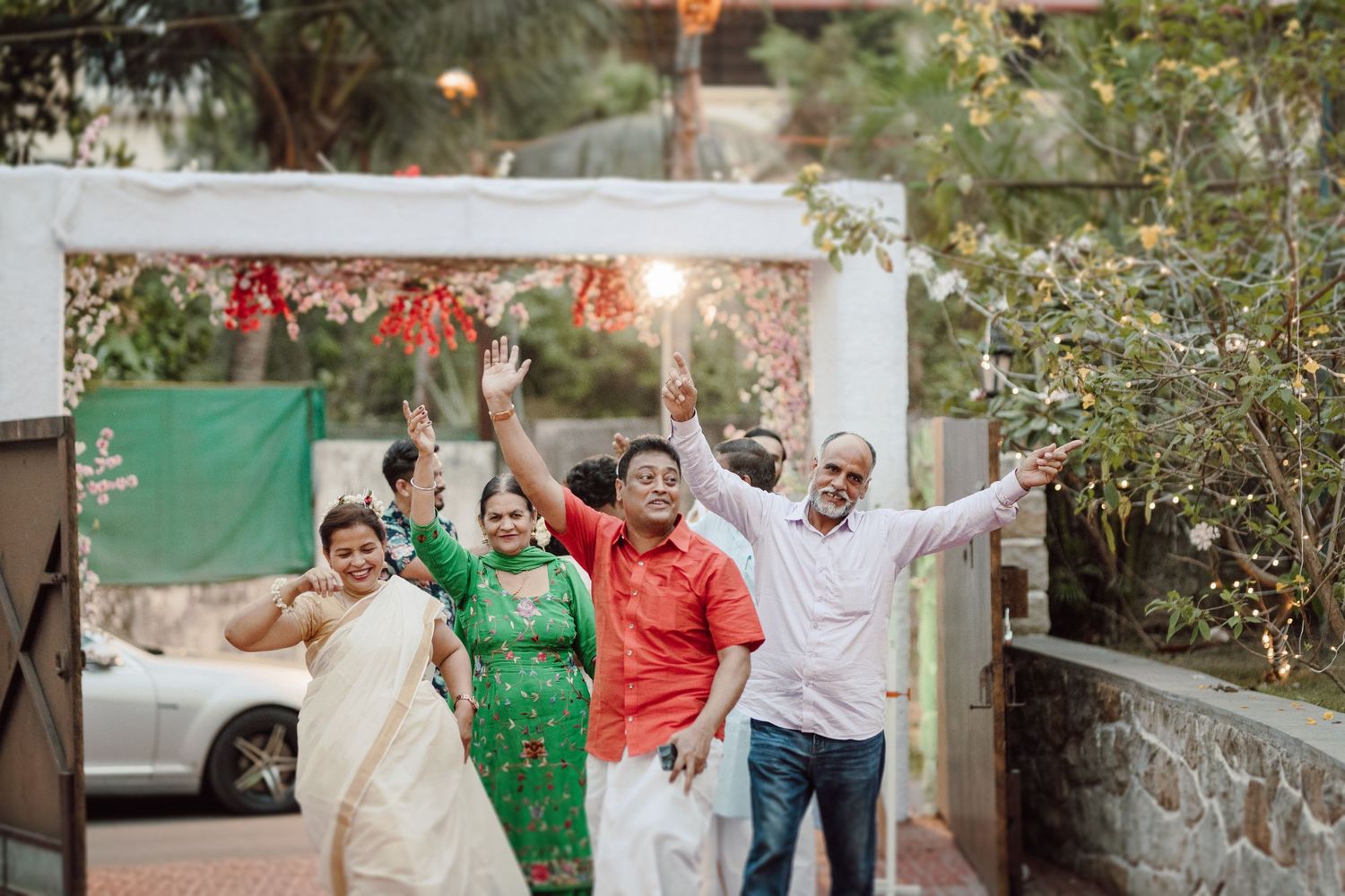 Wedding guests celebrate joyfully in an outdoor garden setting.