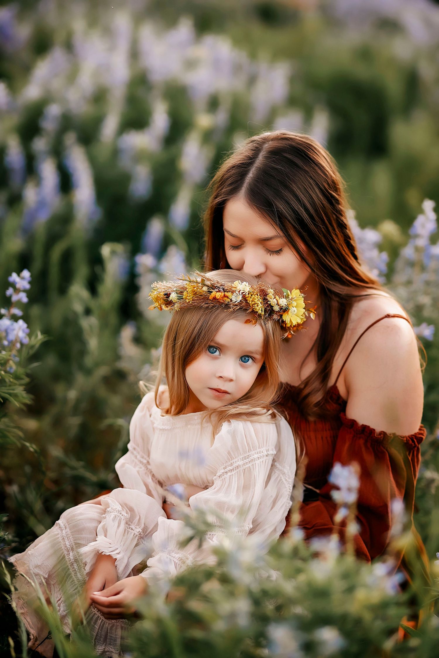 A mother kisses her daughter's head in the flower fields of Crested Butte.