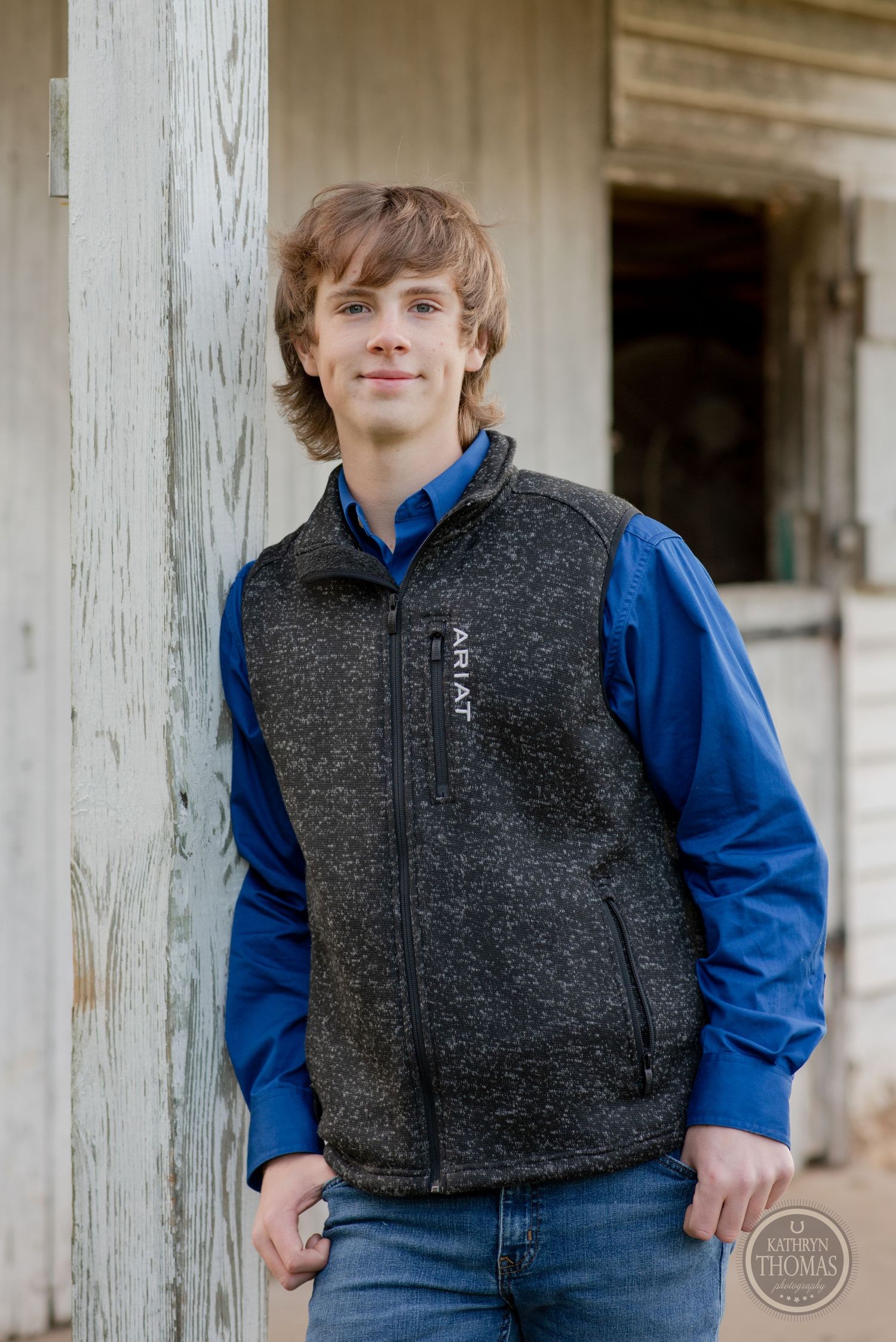 Portrait of someone wearing blue and gray fleece vest against white barn siding.