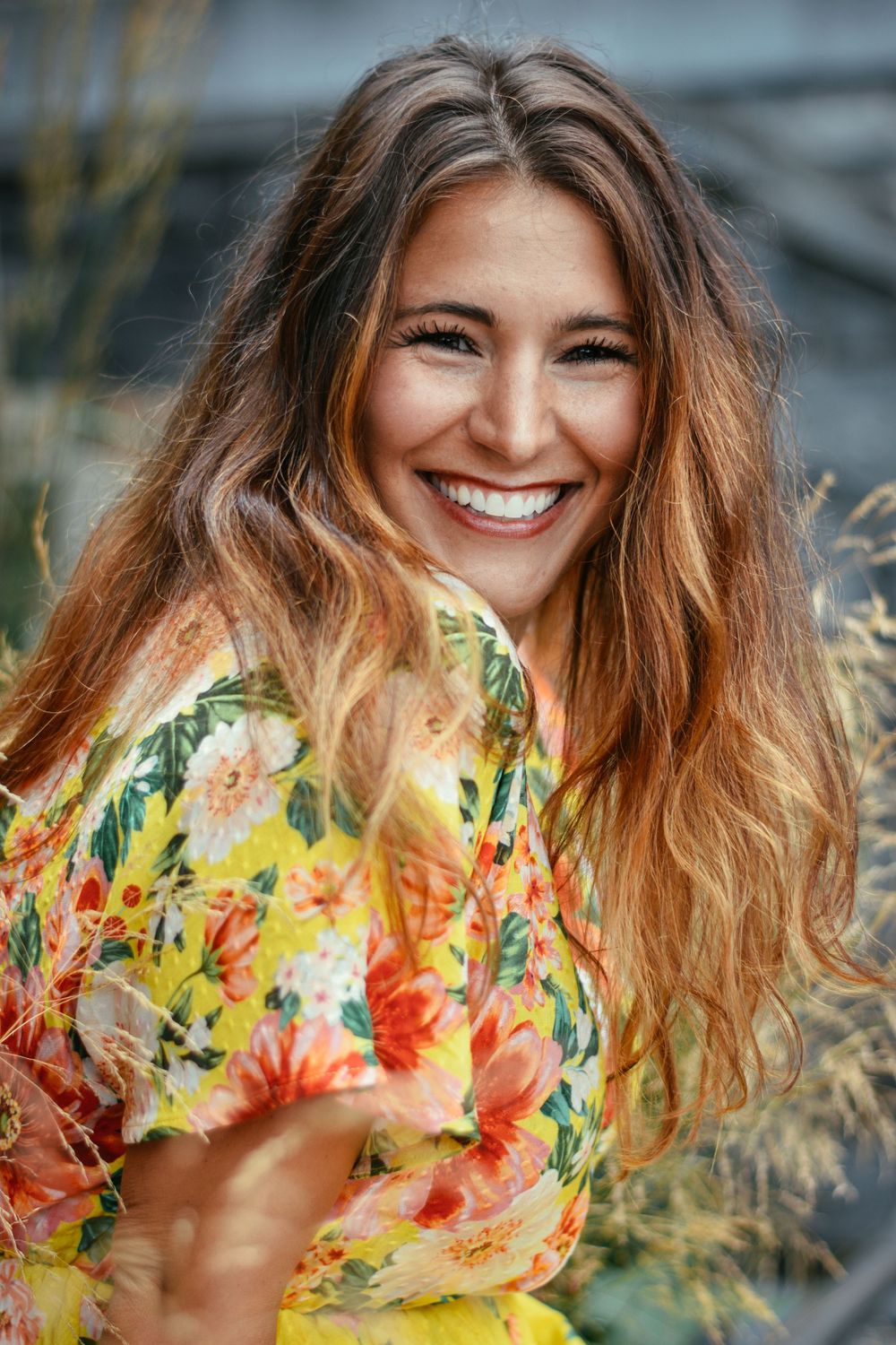 a young woman, smiling in a yellow, flowery dress
