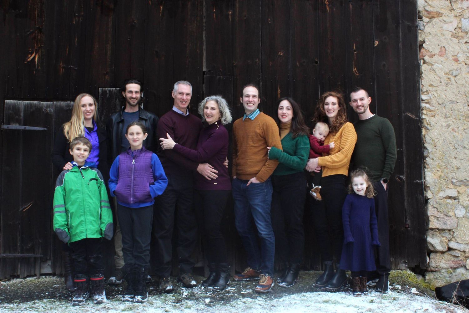 Group portrait of multiple generations gathered in front of a rustic wooden barn door.