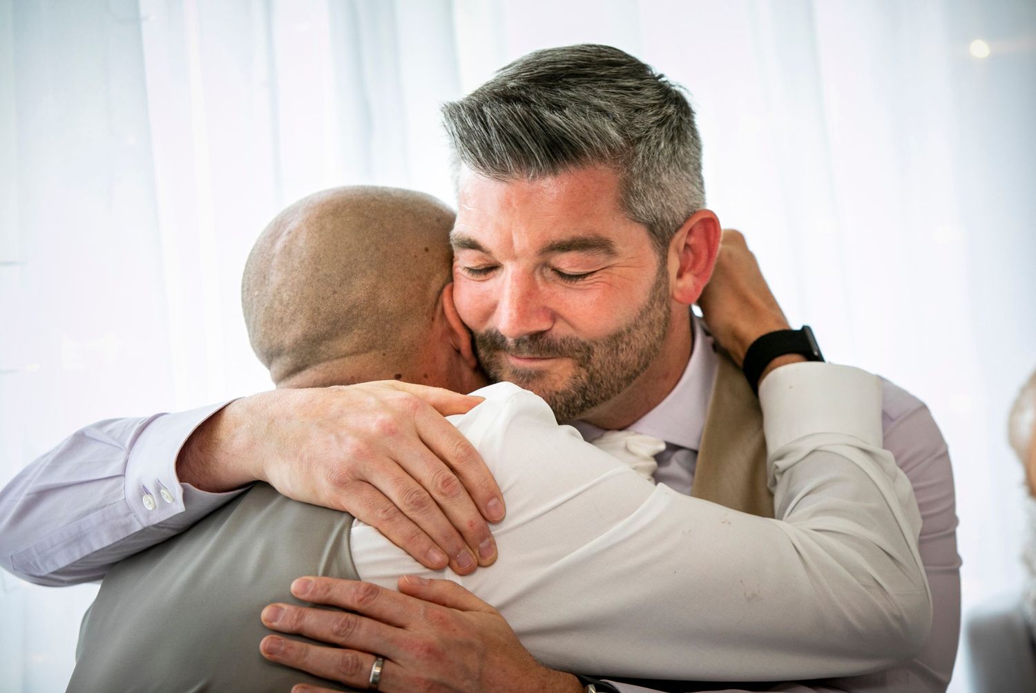 Emotional wedding reception moments captured during speeches with white backdrop.