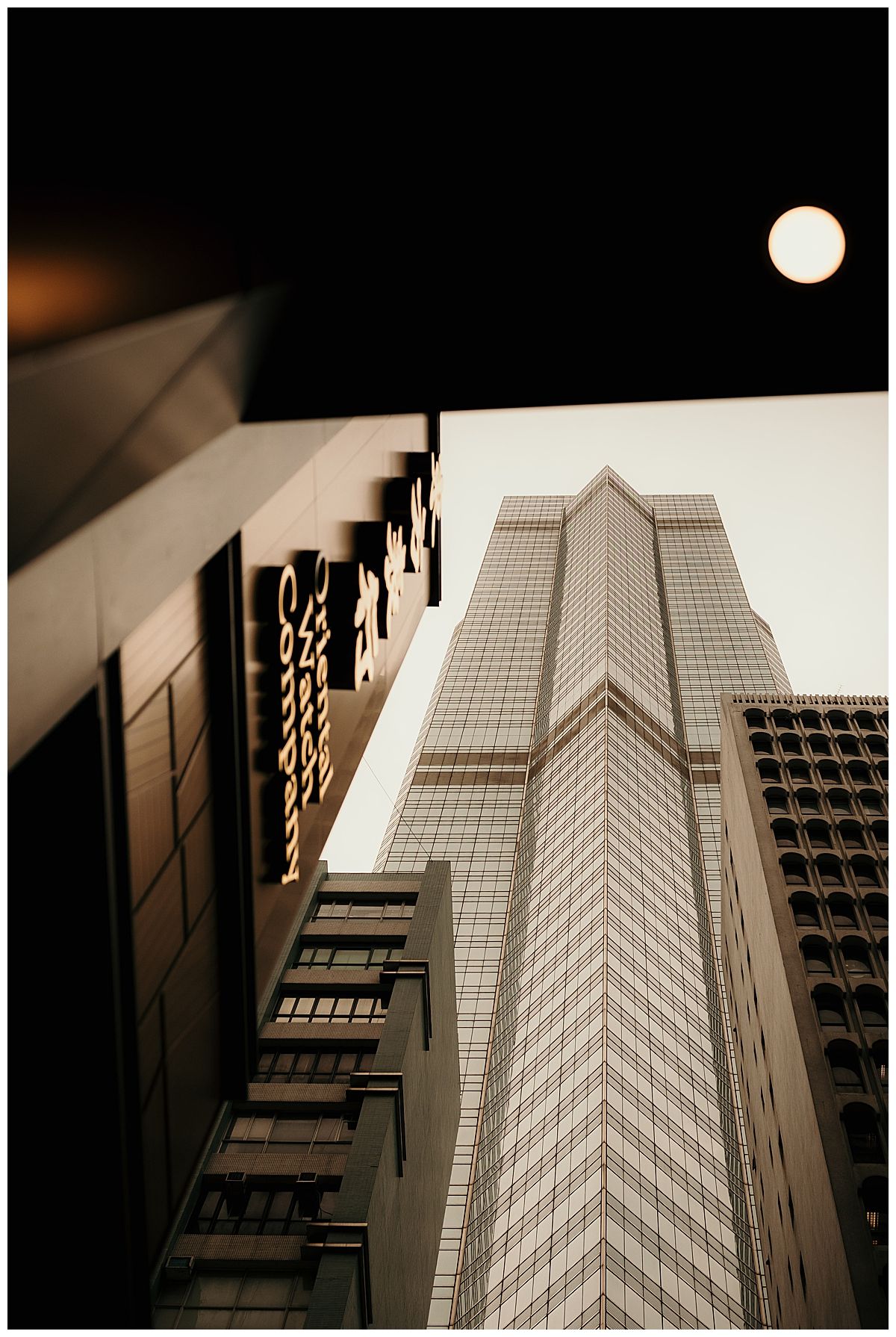 Modern skyscraper photographed from below with a full moon in the night sky.