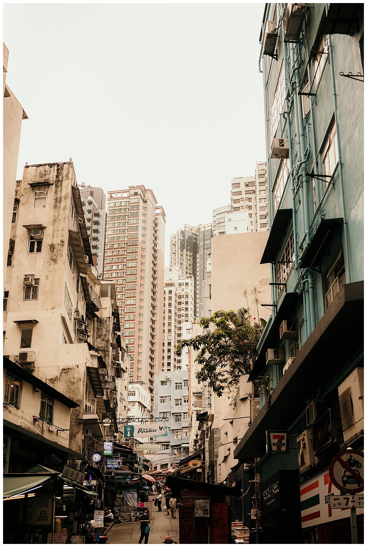 Looking up at towering apartment buildings in a narrow urban street.